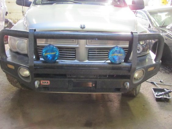 Silver Dodge Ram truck front with ARB bull bar, two blue auxiliary lights, and a winch opening