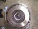 1990 Ford Mustang - A vehicle clutch assembly is shown removed from the vehicle, resting on a concrete surface.