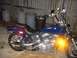 1995 Honda Shadow Sabre VT 1100 - A blue motorcycle is parked in front of a wooden fence with trash cans in the background.