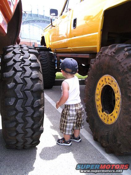 Yellow monster truck with massive tires, child looking up