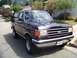 1990 Ford Bronco - This black 1990 Ford Bronco is parked on a residential street, showing its front grille and chrome bumper.