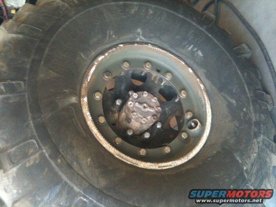 Close-up of a large, off-road tire and wheel assembly with visible lug nuts and a hub