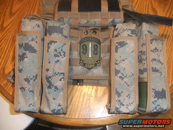 Military vest with camouflage pouches and a patch reading 'OPERATORS 9806'