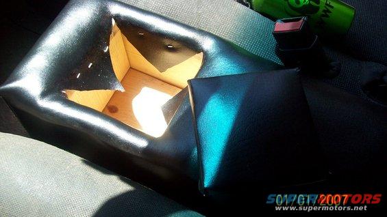 Damaged black vinyl interior car part with exposed wood