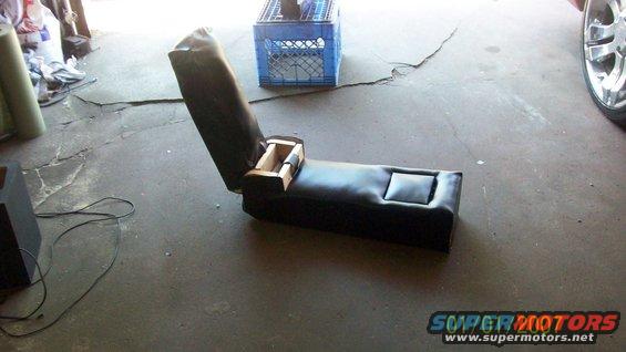 Car seat console with open storage compartment and cup holder, on concrete floor