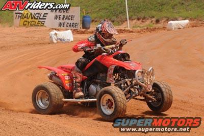 Red 2004 Honda TRX 400 EX ATV with rider on dirt track, front view