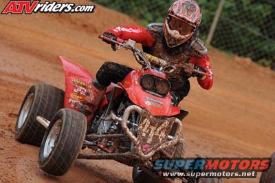 Red ATV with rider on a dirt track. "ATVRiders.com" and "SUPERMOTORS.NET" watermarks visible