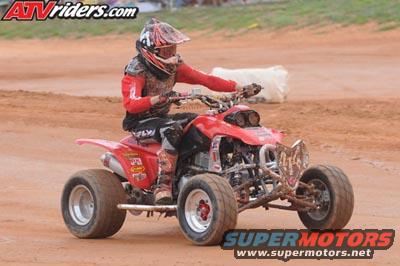 Red 2004 Honda TRX 400 EX ATV with rider on dirt track