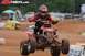 2004 Honda TRX 400 EX - A rider on a red ATV soars through the air during a race, with prominent watermarks from ATVriders.com and Supermotors.net on the image.