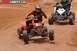 2004 Honda TRX 400 EX - Two ATVs race on a dirt track, with one in the foreground and another behind it.