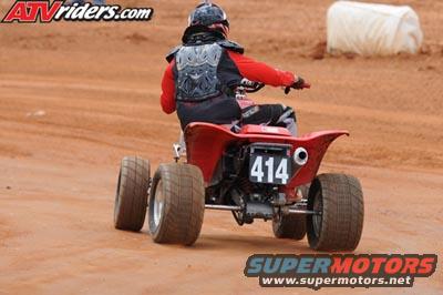 Red ATV with number 414 on the rear fender, rider wearing protective gear, on a dirt track
