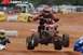 2004 Honda TRX 400 EX - An ATV rider soars through the air during a race, with other competitors and spectators in the background.