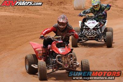 Red ATV in foreground, white ATV with number 238 behind it, racing on dirt