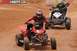 2004 Honda TRX 400 EX - Two ATVs compete on a dusty track, with one rider in red and the other in camouflage gear.