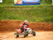 2004 Honda TRX 400 EX - Rider on a red ATV navigates a dirt track with a banner in the background.