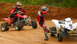 2004 Honda TRX 400 EX - Two ATVs and riders on a dirt track during a race or practice session.