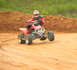 2004 Honda TRX 400 EX - A rider on a red ATV navigates a dirt track, with one front wheel lifted off the ground.