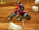 2004 Honda TRX 400 EX - Rider on a red ATV performs a jump on a dirt track, with the number 414 displayed.