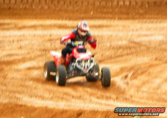 Person riding a red ATV on a dirt track