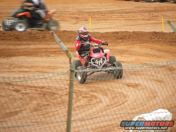 Red ATV with number 414 on front, rider in red gear, on dirt track