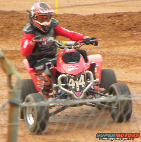 Red ATV with rider wearing helmet and protective gear, number 414 on front