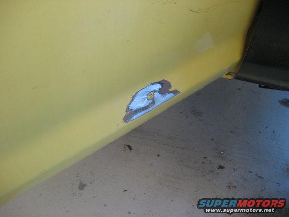 Yellow vehicle side panel with a patch of exposed metal, primer, and blue paint