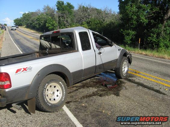Silver pickup truck with black fender flares and FX4 badging, parked on the side of a road with debris on the ground