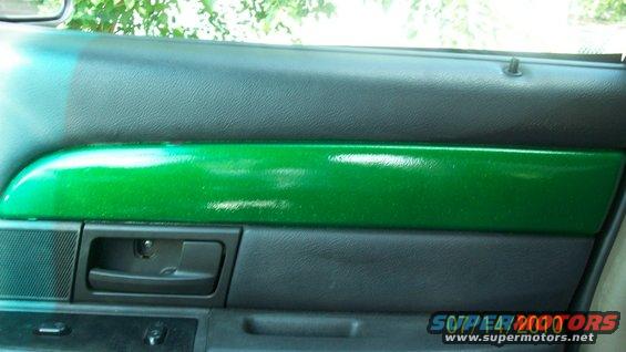 Car door panel with a shiny green trim piece above the black door handle and speaker grille