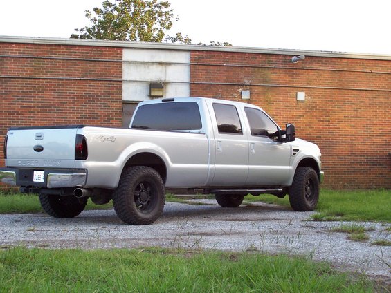 Silver 2008 Ford F-250 Super Duty pickup truck with tinted windows and black wheels parked on gravel