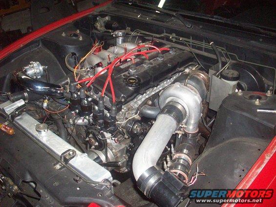 Turbocharged engine bay with red spark plug wires and a large turbocharger