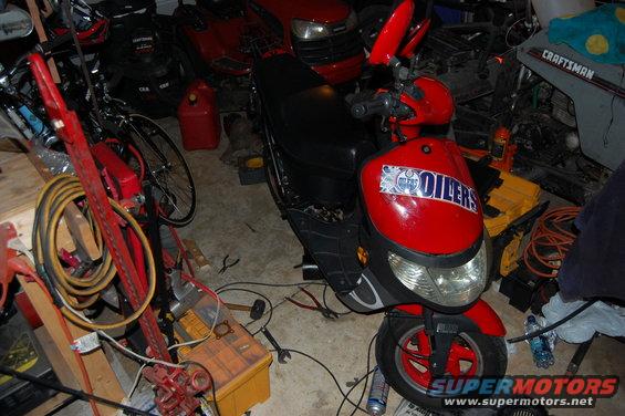 Red scooter with Oilers logo on front, parked in a cluttered garage
