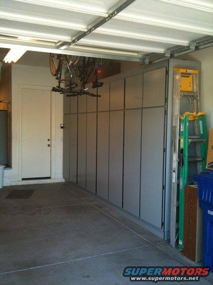 Garage interior with gray cabinets, ladder, and bicycle overhead