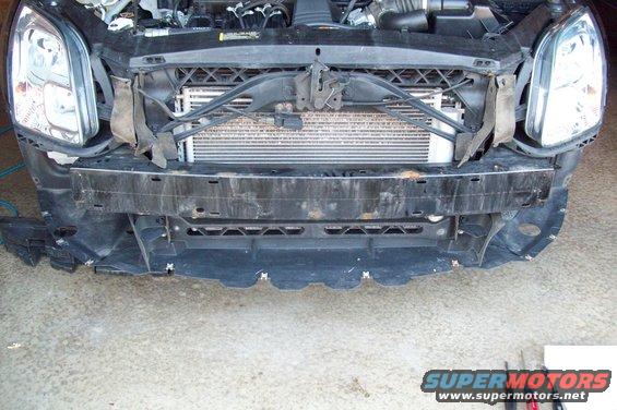Car front end removed, showing radiator and engine components. Headlights visible