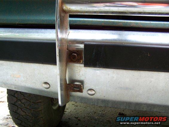 close-up of a vehicle's front bumper and brush guard, showing some rust on the mounting hardware