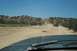 1995 Ford Bronco - View from inside a vehicle looking out at a desert landscape with a dirt road winding through hills.