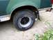 1989 Ford Bronco - Close-up of a truck's rear wheel and fender, showing some rust and a mud flap.