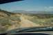 1995 Ford Bronco - The view from inside a vehicle shows a dirt road leading through a dry, scrub-covered desert landscape towards distant mountains.
