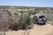 1995 Ford Bronco - A dark green Ford Bronco with a tan top is parked on a dirt road in a dry, hilly area with sparse vegetation.