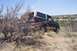 1995 Ford Bronco - A black and tan Ford Bronco is partially obscured by dry brush in a desert-like environment.