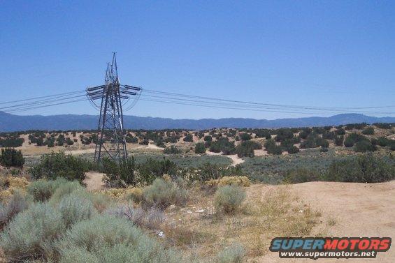 Desert landscape with power lines and mountains under a clear blue sky