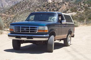 Dark green 1995 Ford Bronco 3q front view on dirt road