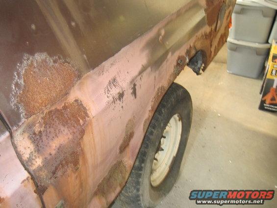 rusted vehicle fender and wheel, showing significant rust damage and primer