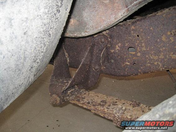 Rusted leaf spring attached to vehicle frame, close-up view