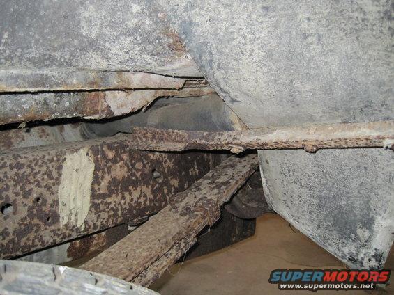 Close-up of heavily rusted leaf springs and frame components under a vehicle