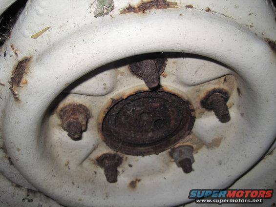 close-up of a rusted wheel hub with five lug nuts