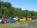 1985 Ford Mustang - A gathering of Ford Mustangs in a scenic outdoor location under a clear blue sky.