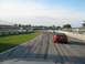 1985 Ford Mustang - A red coupe, likely a 1994 Ford Mustang, navigates a race track with tire marks visible on the asphalt.