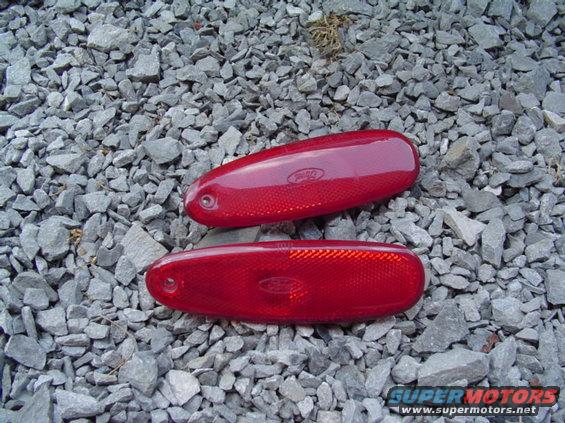 Two red Ford side marker lights on gravel