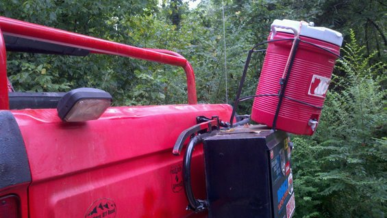 Back of red off-road vehicle with a large red cooler strapped to a rack behind it
