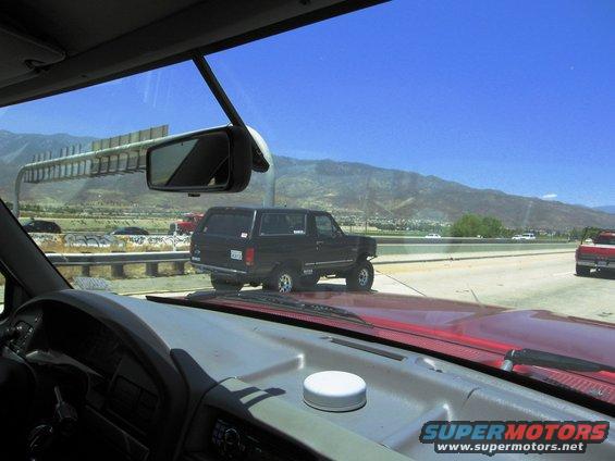 Black SUV driving on highway, seen from inside another vehicle. Mountains in background